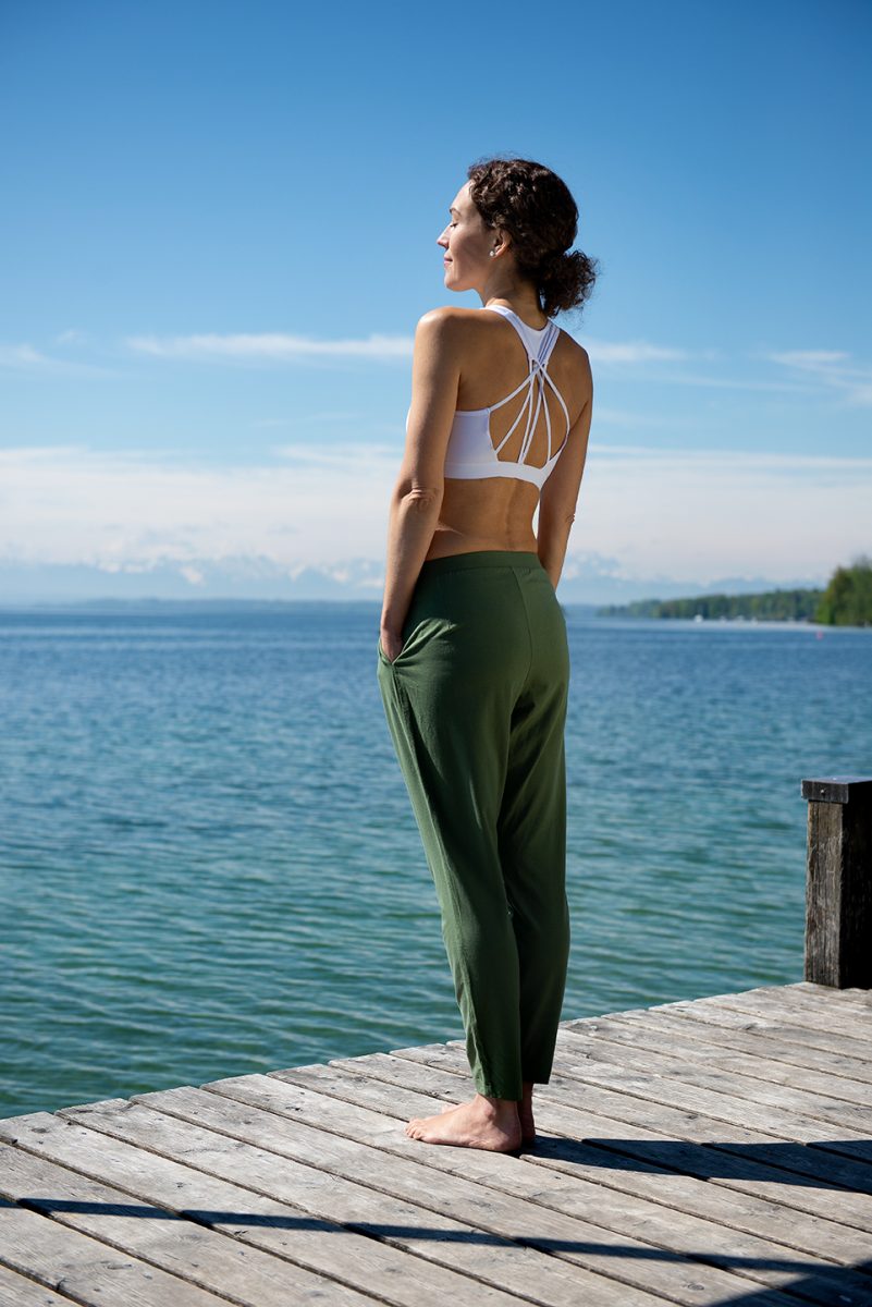 Yogafotografie von Ranja Weis steht auf einem Steg des Starnberger Sees und genießt mit geschlossenen Augen die Sonne und Weite. | Felix Krammer Fotografie